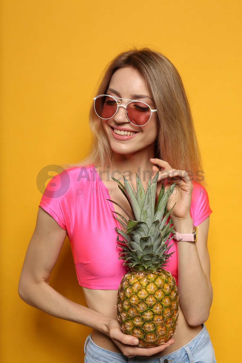 Photo of Young woman with fresh pineapple on yellow background. Exotic fruit