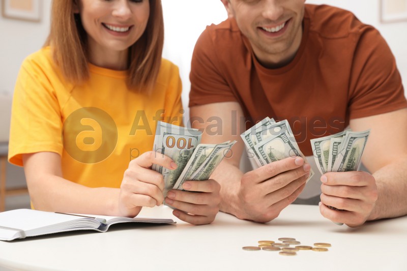 Couple counting money at table indoors, closeup