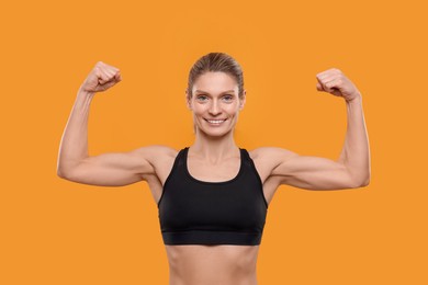 Photo of Portrait of sportswoman showing muscles on yellow background