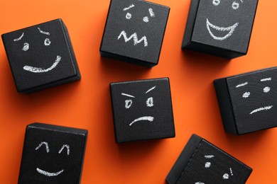 Photo of Many cubes with different emotions on orange background, flat lay. Emotional management