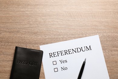 Referendum ballot with pen and passport on wooden table, flat lay. Space for text