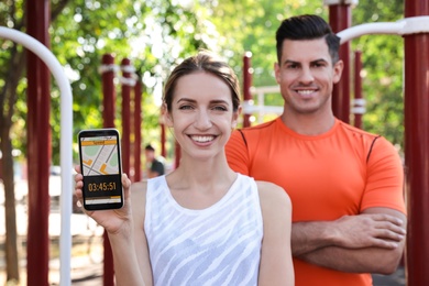 Couple showing smartphone with fitness app on sports ground