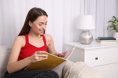 Young woman reading fashion magazine at home