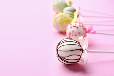 Different tasty cake pops on light pink background. Space for text