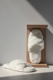 Pair of soft slippers and wooden stand on floor
