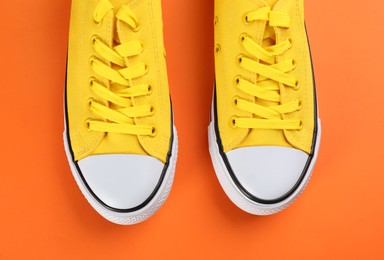 Photo of Pair of trendy sneakers on orange background, flat lay