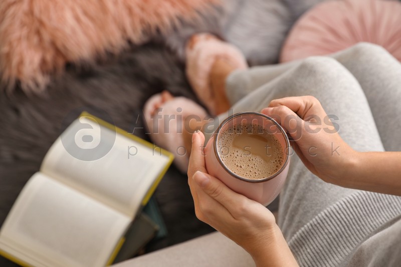 Woman with cup of hot coffee resting at home, above view. Space for text