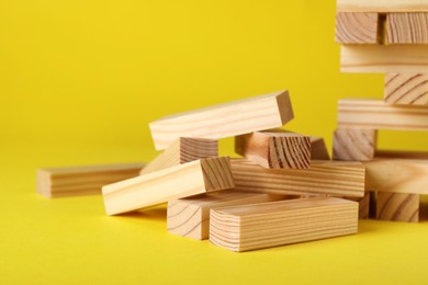 Wooden Jenga blocks on yellow background, closeup