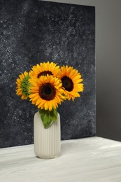 Vase with beautiful sunflowers and double-sided backdrop in photo studio