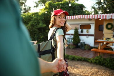 Young woman with travel backpack holding her boyfriend's hand outdoors, closeup. Summer trip