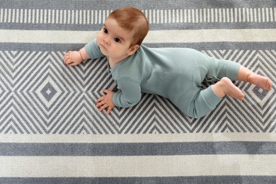 Photo of Cute baby crawling on floor, top view