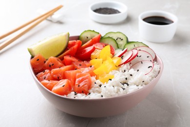 Delicious poke bowl with salmon, rice and vegetables served on light grey table