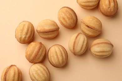 Photo of Homemade walnut shaped cookies with condensed milk on beige background, flat lay