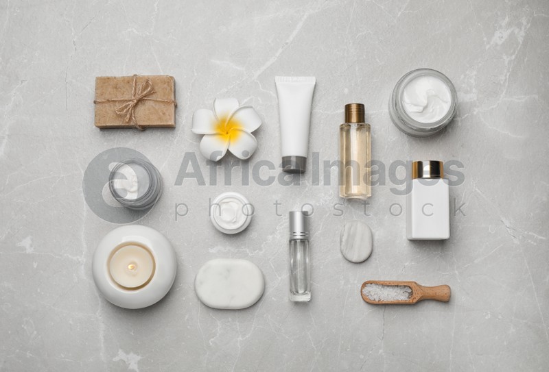 Flat lay composition with cosmetics and sea salt on grey marble table. Spa treatment