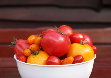 Photo of Bowl with fresh tomatoes on wooden surface, closeup
