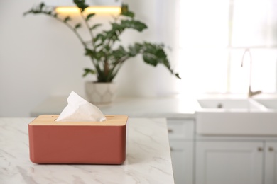 Box with paper tissues on white marble table in kitchen. Space for text
