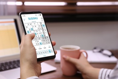 Woman playing sudoku game on smartphone indoors, closeup