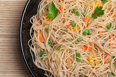 Top view of pan with delicious asian noodles and vegetables on table, closeup