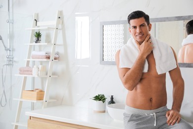 Handsome man touching his smooth face in bathroom after shaving