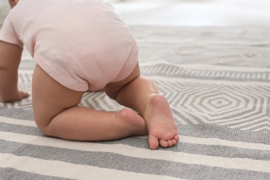 Baby crawling on floor at home, closeup