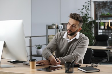 Man working on computer at table in office