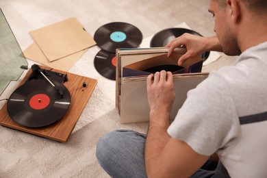 Man with collection of vinyl records near turntable at home