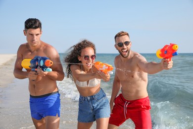 Friends with water guns having fun on beach