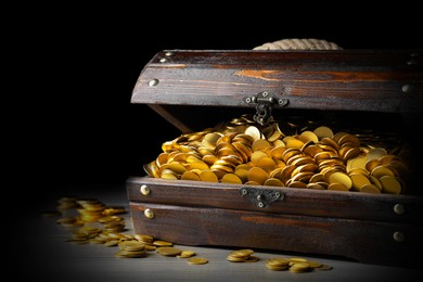 Image of Open treasure chest with gold coins on grey wooden table