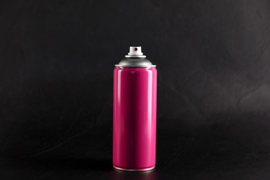 Pink can of spray paint on black background