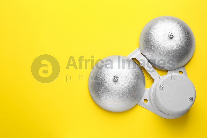 Modern electrical school bell on yellow background, top view. Space for text
