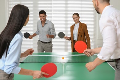 Business people playing ping pong in office