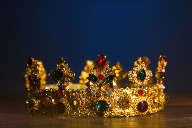 Beautiful golden crown with gems on wooden table. Fantasy item