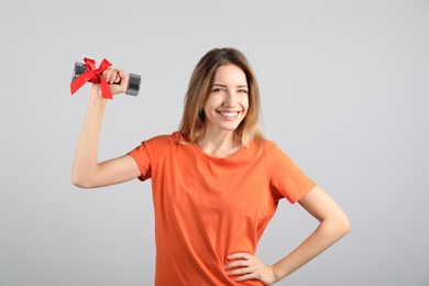Woman with dumbbell as symbol of girl power on light grey background. 8 March concept