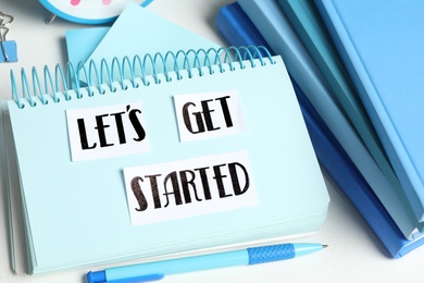 Sheets of paper with phrase Let's Get Started and stationery on white table, closeup
