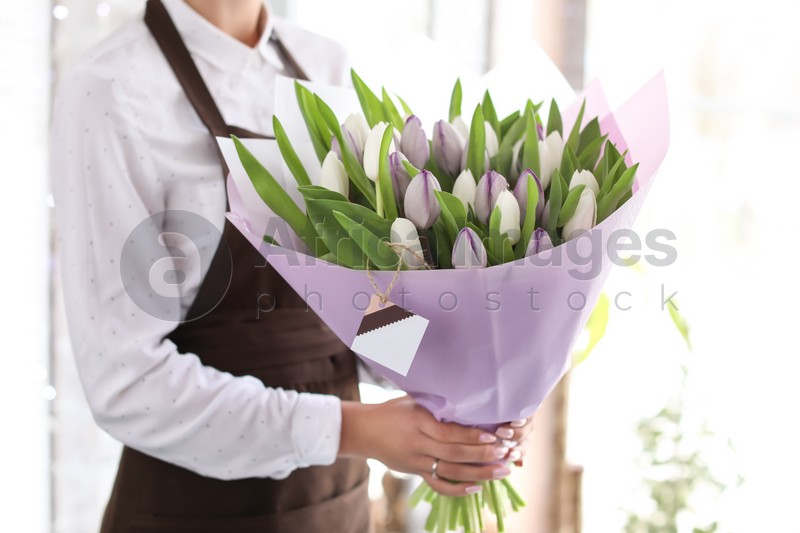 Female florist holding bouquet of beautiful flowers in shop