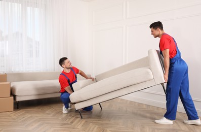 Professional movers carrying sofa in new house