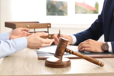 Gavel and blurred lawyer working with client on background