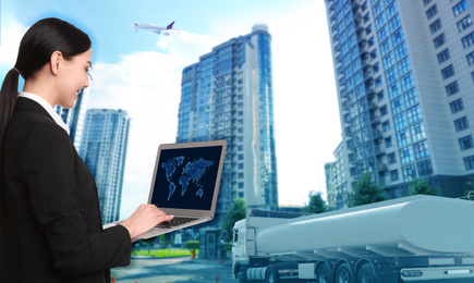 Logistics concept. Businesswoman using laptop with world map. Truck, plane and buildings on background, toned in blue
