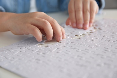 Little girl playing with puzzles at table, closeup