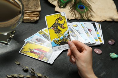 Woman with tarot cards at black table, closeup