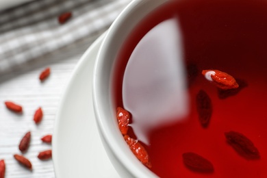 Healthy goji tea in cup on white table, closeup