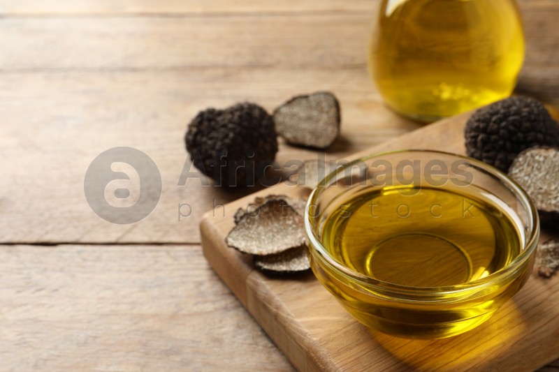 Glass bowl of truffle oil with board on wooden table. Space for text