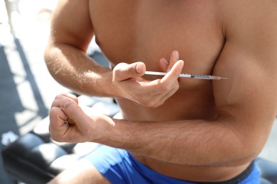 Athletic man injecting himself indoors, closeup. Doping concept