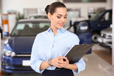 Portrait of young saleswoman in car dealership