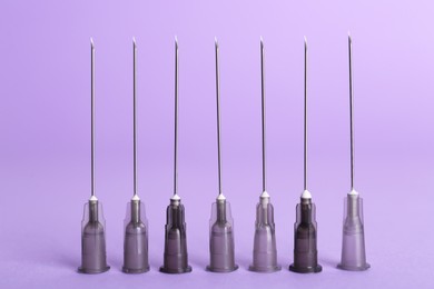 Many disposable syringe needles on violet background