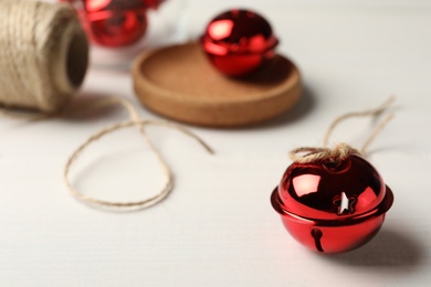 Red sleigh bell with rope on white table. Space for text