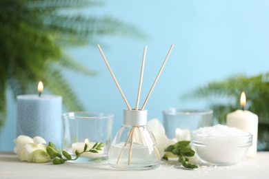 Photo of Beautiful spa composition with reed diffuser and candles on white table