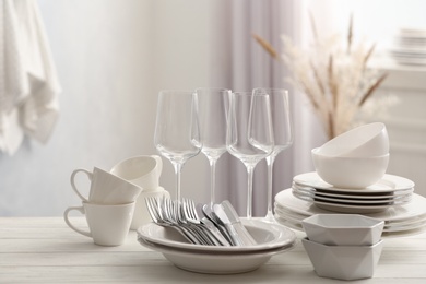 Set of clean dishware, cutlery and wineglasses on white table indoors