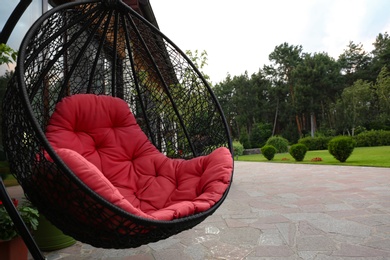 Comfortable swing chair with pink pillow near house. Garden furniture