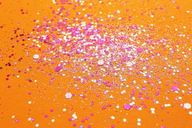 Photo of Shiny bright pink glitter on orange background